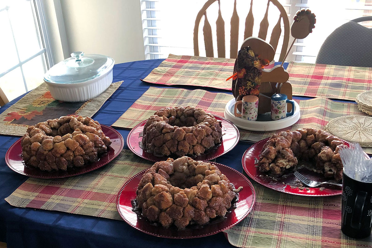 Table set with plaid plaid placemats and four monkey breads on plates: Bundt cake-like rings of golden brown balls of dough.